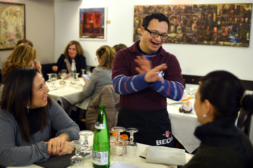 a young man with Down syndrome, jokes with clients as he works in the restaurant &#8220;Locanda dei Sunflowers&#8221; &#8211; en