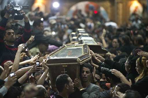 Egyptian Copts carry four coffins down the aisle of the Virgin Mary Coptic Christian church – en