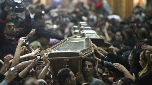 Egyptian Copts carry four coffins down the aisle of the Virgin Mary Coptic Christian church – en