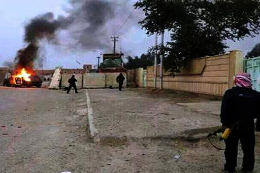 IRAQ, Mosul : A picture taken with a mobile phone shows an armed man watching as a vehicle is seen in flames &#8211; en