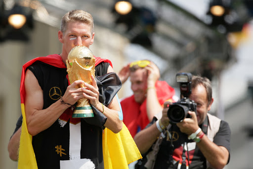 Bastian Schweinsteiger (L) kisses the World Cup trophy during the welcome reception for Germany&#8217;s national soccer team/Brandenburg Gate, Berlin, Germany, 15 July 2014. &#8211; en