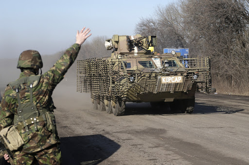 Ukrainian soldier waves to armored vehicle on the road to Debaltseve