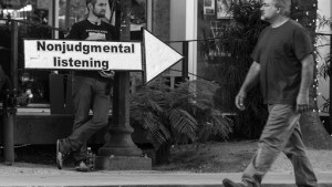 Man standing behind “nonjudgmental listening” sign
