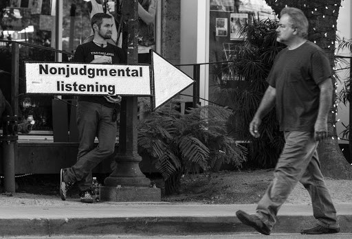 Man standing behind &#8220;nonjudgmental listening&#8221; sign