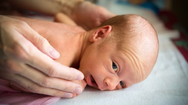 WEB-CHILD-INFANT-FACE-DOWN-HANDS-MAN-Aliaksei-Smalenski-Shutterstock_247860178