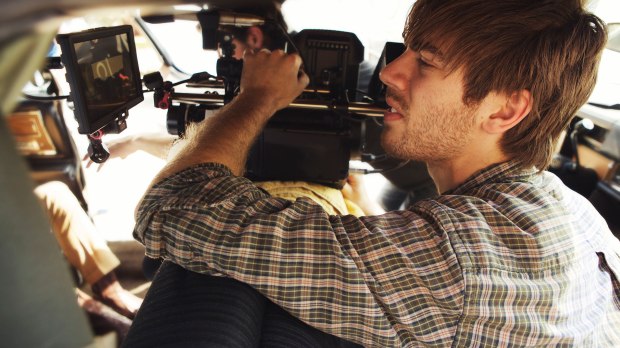 A male filming with a camera for production