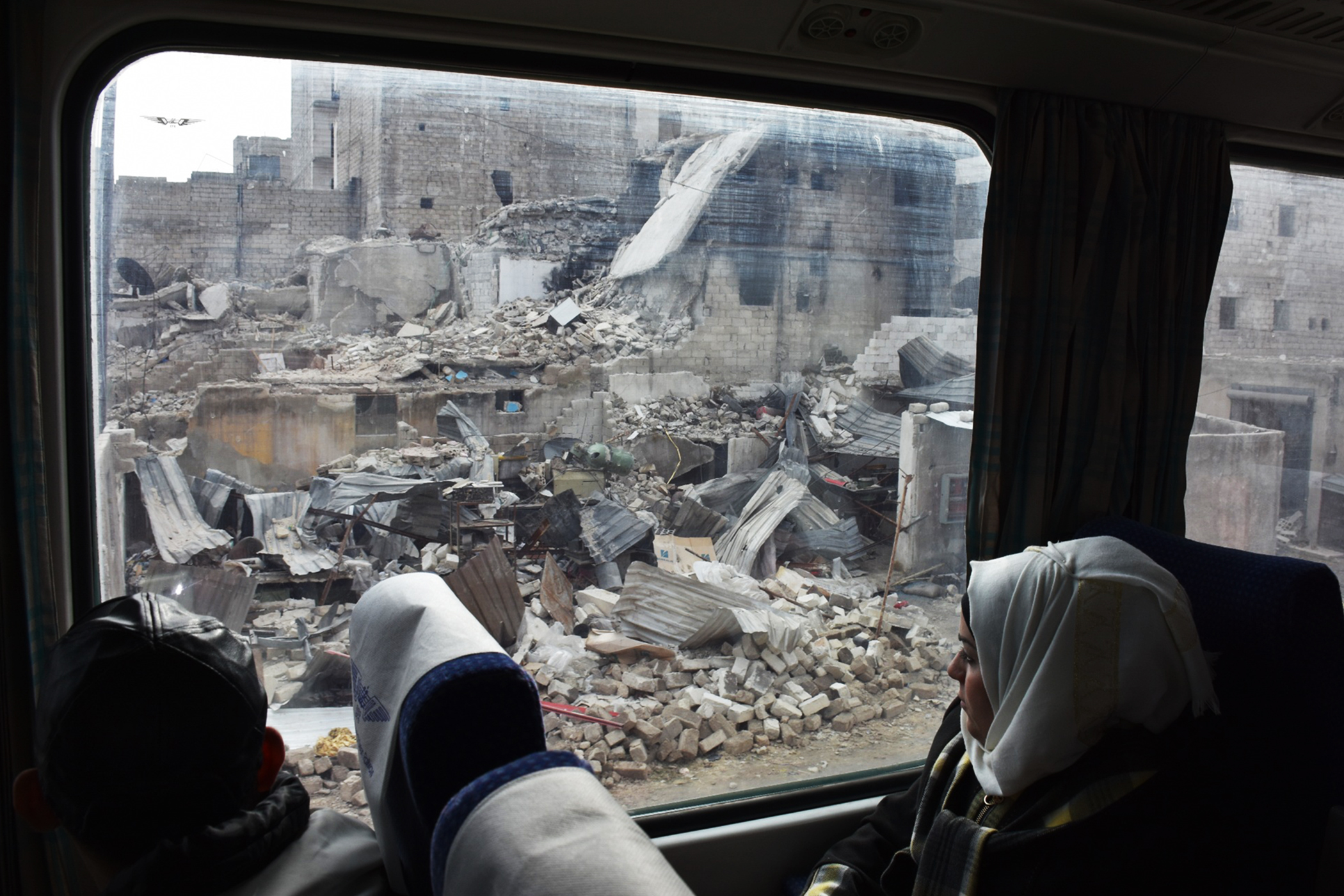 A Syrian woman peers out the window as she sits in a train travelling through Aleppo's devastated eastern districts for the first time in more than four years, on January 25, 2017. It is the train's first such trip since rebels overran east Aleppo in the summer of 2012, effectively dividing the northern city into a regime-held west and a rebel-controlled east. / AFP PHOTO / George OURFALIAN