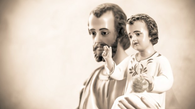 Artistic vintage sepia edit of a classical church statue of baby Jesus blessing, held by St Joseph. Artistic selective focus.