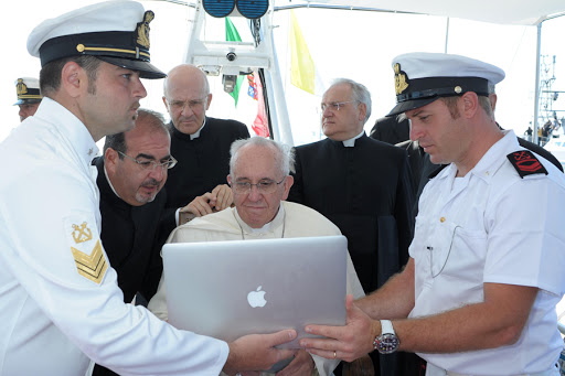 Pope Francis looking at a computer while receiving explanations on a boat off Lampedusa island &#8211; AFP &#8211; fr