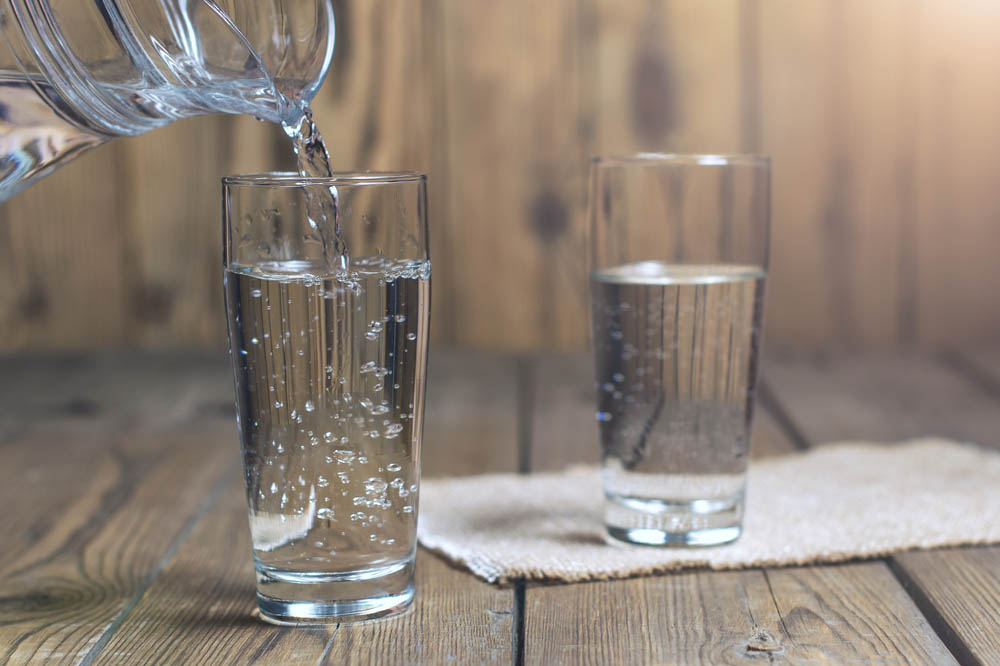 WEB-Glass of water on a wooden table-shutterstock_501781486-By SedovaY-AI