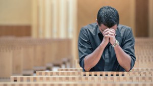 YOUNG MAN PRAYING AT CHURCH