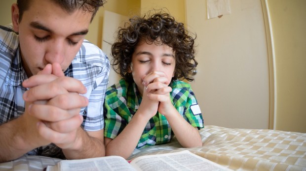 WEB3-YOUNG-BOYS-PRAYING-CHILDREN-YOUTH-BEDROOM-BIBLE-shutterstock_132972143-Shutterstock