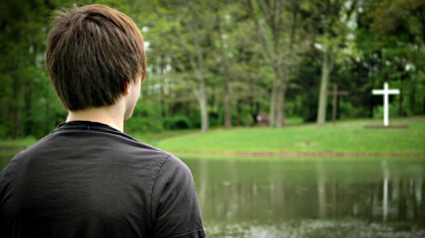 YOUNG MAN LOOKING AT CROSS ACROSS THE POND