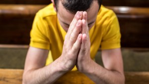 MAN PRAYING IN CHURCH PEW