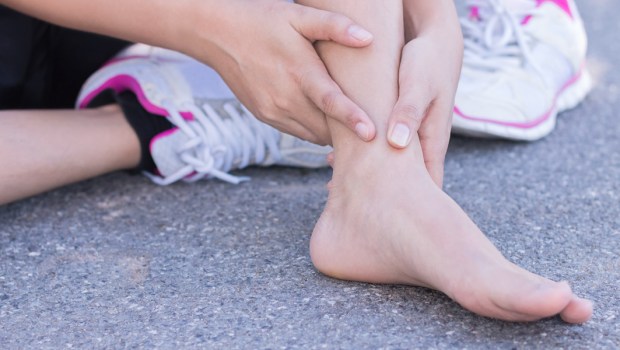 WOMAN HOLDING HER ANKLE