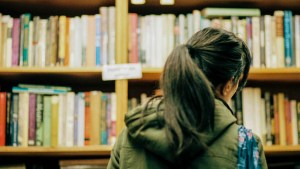 WOMAN LOOKING AT BOOKSHELF