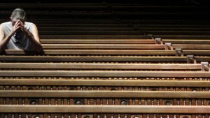 MAN PRAYING IN PEW