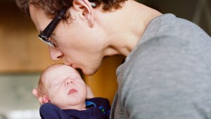 FATHER KISSING NEWBORN