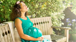 PREGNANT WOMAN SITTING IN PARK