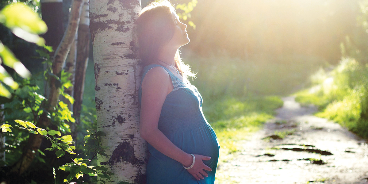 Pregnant woman standing in forrest an drelaxing