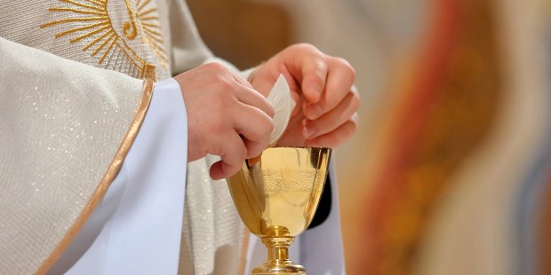 Why do priests drop a piece of host into the chalice?