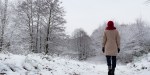 Woman in red knit had standing before snowy forest