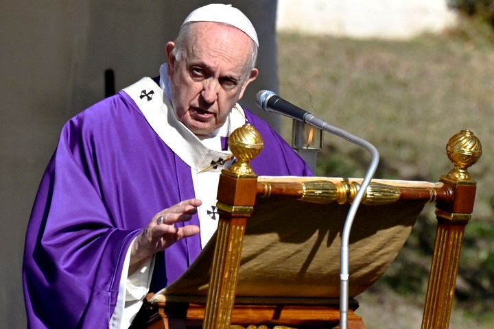 Pope Francis stands by graves with flowers at the French military cemetery