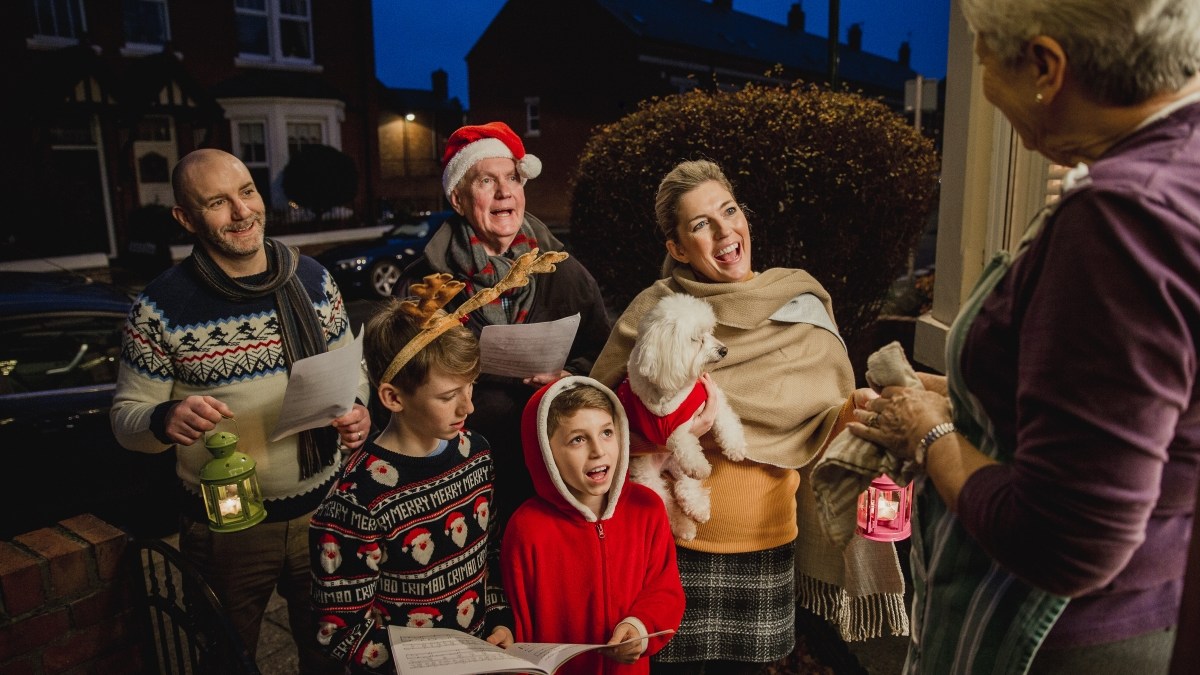 A multi-generational family Christmas caroling at neighboring house