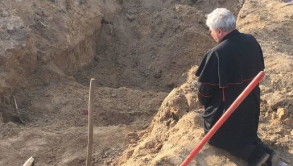 Cardinal Konrad Krajewski prays at a mass grave in Ukraine