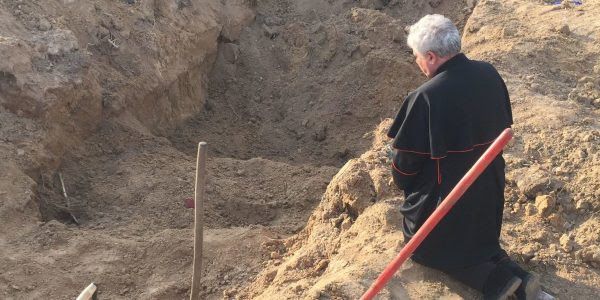 Cardinal Konrad Krajewski prays at a mass grave in Ukraine