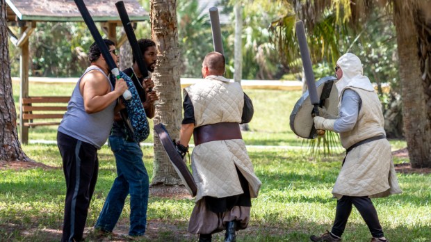 Grown men participating in Live Action Role Play (LARP) with fake swords, in costume