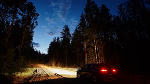 samochód jadący przez las nocą po piaszczystej drodze