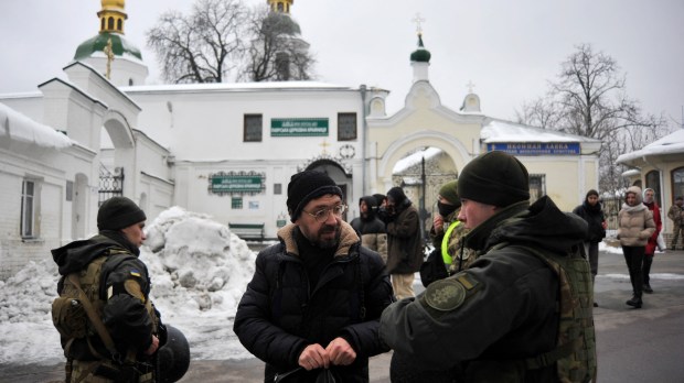 Soldier checking visitor at Ukraine monastery