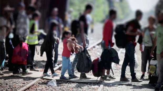 refugees and migrants cross train tracks