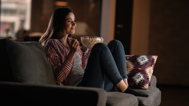 Beautiful woman watching movie in the night sitting on a couch in the living room at home