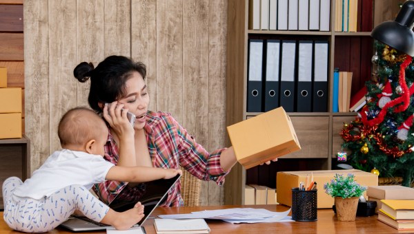 Asian woman with baby working at home using laptop