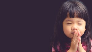 Young girl praying silently with eyes closed