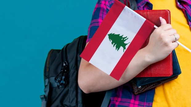 Pupil holds book bag and Lebanese flag