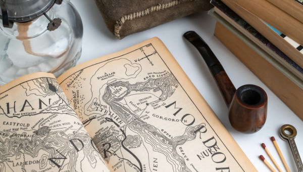Mapa Śródziemia na stole obok fajki, zapałek, lampy i książek