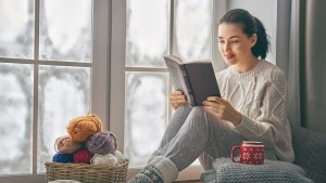 kobieta zimową porą czyta na parapecie okna wartościowe książki