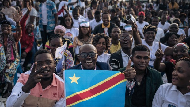 A man holds a Democratic Republic of Congo flag as attendees gather ahead of the arrival of Pope Francis for the mass at the N'Dolo Airport in Kinshasa