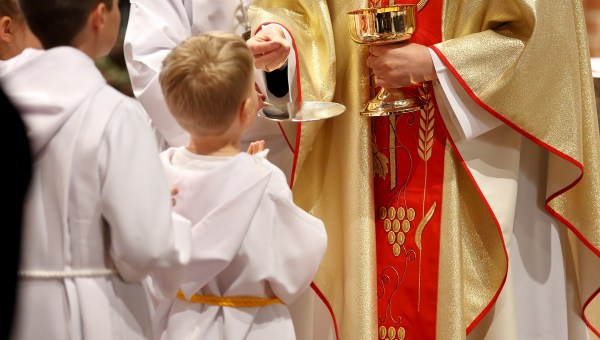 Altar boy in robes receives the Eucharist