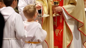 Altar boy in robes receives the Eucharist