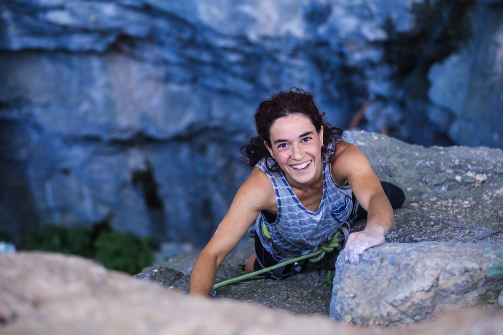 smiling young woman rock climbing