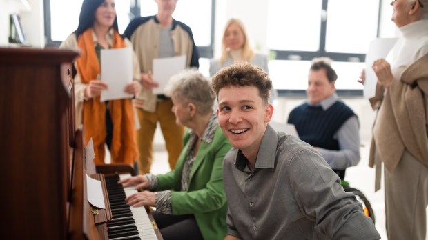 seniors with young man singing around piano at church