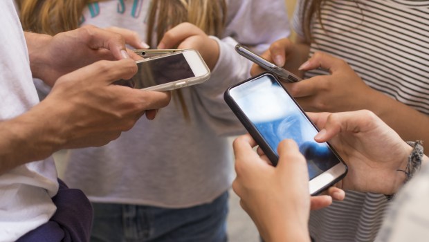 group of young people with mobile phones on the street