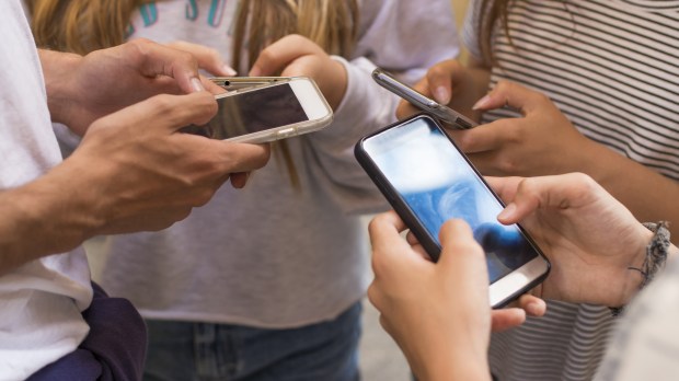group of young people with mobile phones on the street