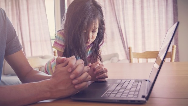 Father and daughter pray at computer