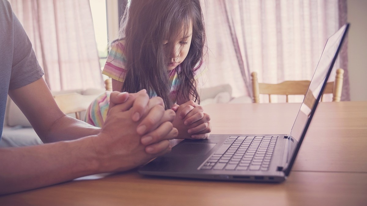 Father and daughter pray at computer