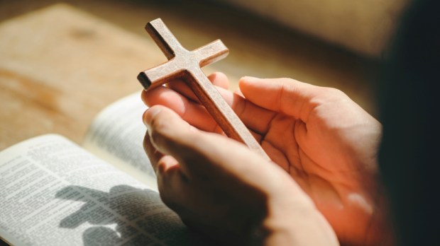 man hands praying to god with the bible and cross